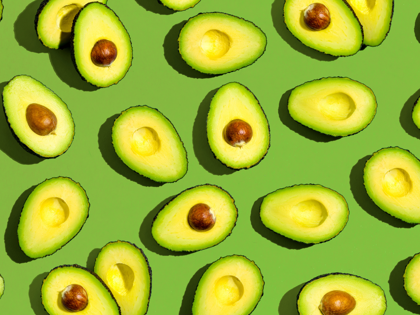 Fresh avocado pattern on a green background flat lay